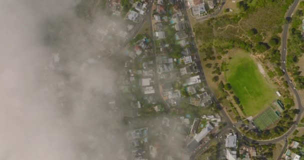 Terbang di atas kota pesisir, jarak pandang yang terbatas naik dari laut. Rumah-rumah, jalan-jalan dan daerah olahraga di lingkungan perkotaan. Cape Town, Afrika Selatan — Stok Video