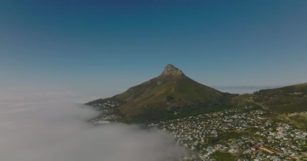 Vista panorámica aérea de los Leones Cabeza de montaña que se eleva por encima del barrio residencial y la costa del mar cubierta de densa niebla. Ciudad del Cabo, Sudáfrica — Vídeos de Stock