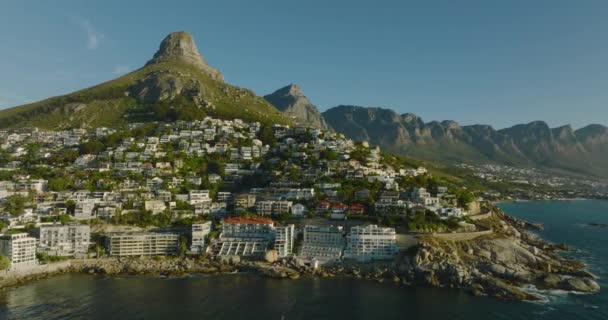 Voe em torno da costa marítima alinhada por propriedades de luxo e hotéis. cume de montanha de rocha no fundo. Cidade do Cabo, África do Sul — Vídeo de Stock