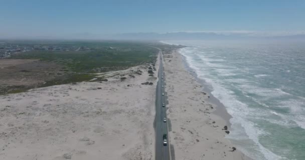 Foto descendente aérea de coches conduciendo por carretera a lo largo de la costa oceánica. olas de mar lavado playa de arena. — Vídeos de Stock