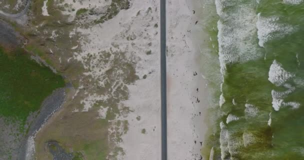 Z góry na dół materiał z wybrzeża morskiego z samochodami jadącymi po prostej drodze. Biały piasek i fale oceaniczne. — Wideo stockowe