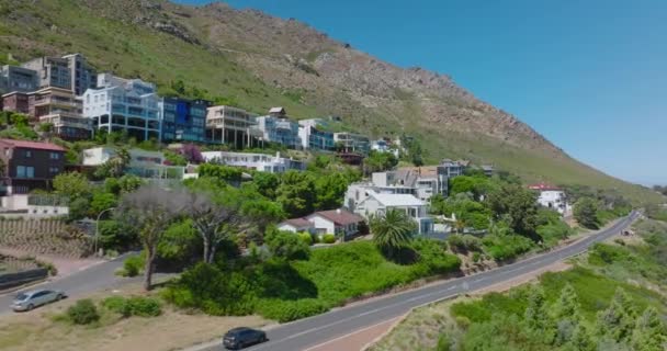 Fliegen Sie durch luxuriöse Appartements und Gästehäuser im tropischen Ferienort. Gebäude in Hanglage entlang der Straße. — Stockvideo