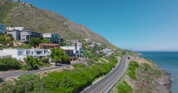 Casas luxuosas rodeadas de plantas verdes. Estrada que conduz ao longo da costa do mar no dia ensolarado em destino de férias tropicais. — Vídeo de Stock