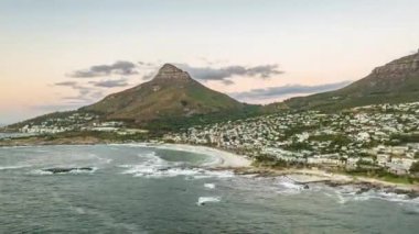 Deniz körfezindeki su kumsalları yıkıyor, deniz kıyısındaki turistik bölgelerde konut binaları yıkıyor. Alacakaranlıkta deniz kıyısının yüksek hızda görüntüsü. Güney Afrika