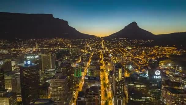 Framåt flyger över upplysta gator i staden i skymningen. Aerial hyperlapse bilder av stadsutveckling med bord berg i fjärran. Sydafrika — Stockvideo