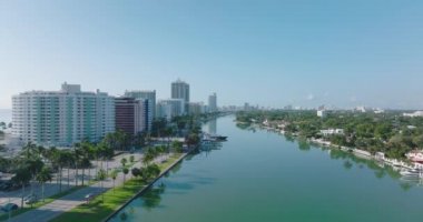 Güneşli bir günde, şehrin sakin su yüzeyinde ileriye doğru uçarlar. Şehir merkezindeki yüksek apartman daireleri sırasına dizilmiş. Miami, ABD