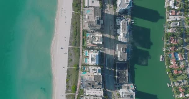 都市部の高層ビルが並ぶ広い道路上のトラフィックのトップダウンビュー。ターコイズブルーの水に囲まれた狭い土地。アメリカ・マイアミ — ストック動画