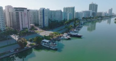 Rıhtım boyunca demirlenmiş yatlar. Uzun binalar boyunca uzanan dere ve çok şeritli yolun havadan görüntüsü. Miami, ABD