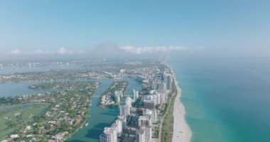 İleriye doğru, deniz kıyısındaki sahil boyunca uzanan modern yüksek binaların üzerinde uçar. Şehrin hava panoramik görüntüleri. Miami, ABD