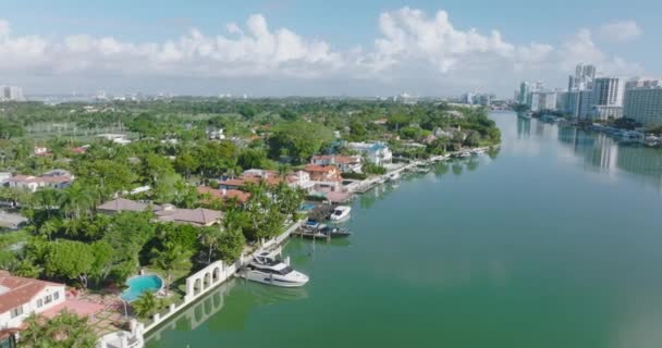 Letecký pohled na luxusní městskou čtvrť s nádhernými rezidencemi podél vodní hladiny. Tropická oblast se zelenou vegetací a palmami. Miami, USA — Stock video