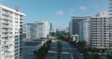 Çok katlı çok katlı apartmanlarla şehir merkezine giden çok şeritli ana yolun üzerinde ilerliyorlar. Miami, ABD