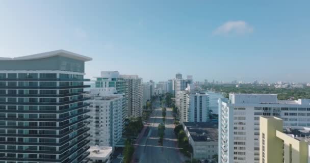 İleri, yüksek modern binalar arasında yolun üzerinden uçar. Deniz kıyısındaki lüks daireler ya da oteller. Miami, ABD — Stok video