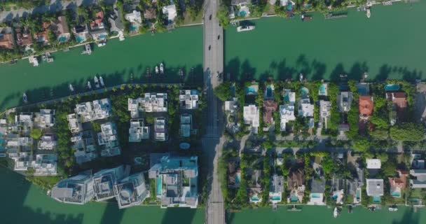 Luxurious residences along water channel with yachts moored at bank. Top down view of urban neighbourhood on sunny day. Miami, USA — ストック動画