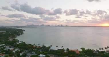 Su yüzeyinin romantik panoramik görüntüsü ve uzaktaki gökdelenlerin siluetleri. Gün batımında hava manzarası. Miami, ABD