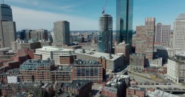 Forvetler şehir mahallelerinin üzerinde uçar. Yeni binanın daralma alanı ve etrafındaki gökdelenin parlak cam cephesindeki yansıması. Boston, ABD