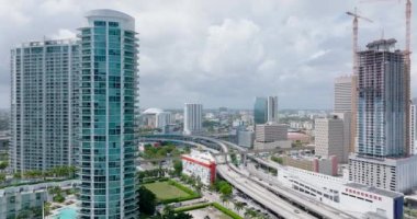 Şehirdeki çok katlı otoyol kavşağı. İleri, modern yüksek katlı konut kulesinin etrafında uçar. Miami, ABD