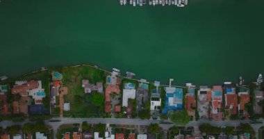 Nehir boyunca lüks bir yerleşim bölgesinin kuş bakışı manzarası. Tekneler ve yatlar arkada demirli. Limana giden yoğun bir otoyol var. Miami, ABD
