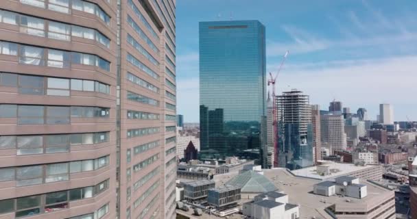 Snímek a pánev kancelářských budov ve vyšších polohách. Moderní mrakodrap s lesklou skleněnou fasádou a staveništěm dalšího. Boston, USA — Stock video