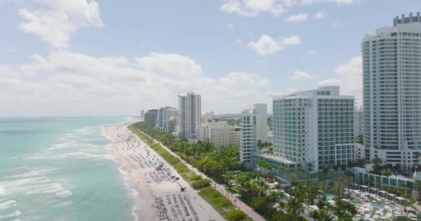 Fila de edifícios modernos de vários andares. Vista aérea de hotéis ao longo da praia de areia na costa do mar. Miami, EUA — Vídeo de Stock