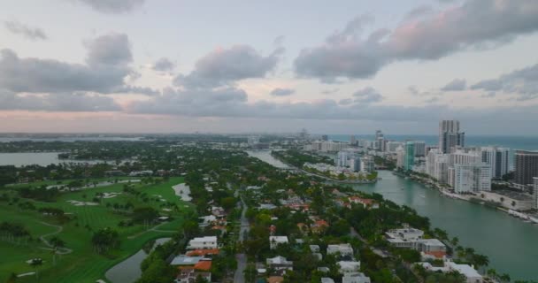 Flygfoto över bostadsområden i skymningen. Sliding avslöja golfbana med palmer. Miami, USA — Stockvideo