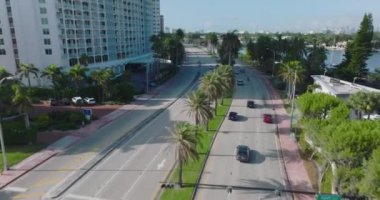 Gelişmiş palmiye ağaçlarıyla kaplı çok şeritli ana yoldaki araçların izini sürüyoruz. Tropik bölgedeki modern şehir ilçesi. Miami, ABD