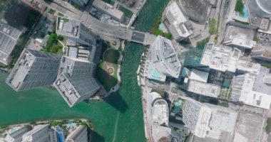 Yüksek binaları ve gökdelenleri olan fütüristik şehir merkezinin kuş bakışı manzarası. Nehirdeki turkuaz suyun üzerindeki çok şeritli yol köprüsü. Miami, ABD