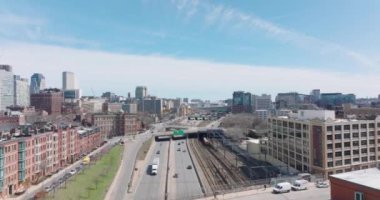 Şehir civarındaki demiryolu hattı boyunca giden kalabalık ana yolda giden araçlar. İleri, kasabanın üstünden uçar. Boston, ABD