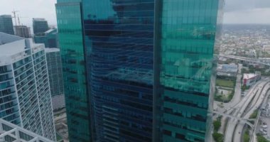 Modern yüksek binaların üzerinden uç. Çevredeki binaları yansıtan renkli cam cephe. Miami, ABD
