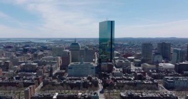 Şehir merkezinin üzerinde ilerliyorlar. John Hancock Kulesi 'nin parıltılı cam cephesi çevreyi yansıtıyor. Boston, ABD