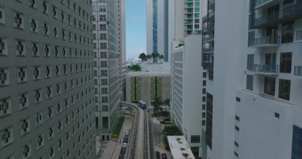 Yüksek binalar arasında giden raylarda giden demiryolu aracının havadan yükselen görüntüleri. Geleceğin yolcu taşımacılığı kavramı. Miami, ABD — Stok video