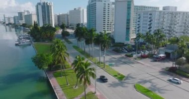 Tropikal bölgede modern lüks bir mahalle. Çok katlı apartmanlar arasında giden çok şeritli yolda giden arabalar. Miami, ABD