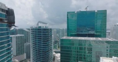 Modern şehir kenti ve parlak cam cepheli uzun gökdelenler. İleri, yüksek binaların üzerinden uçar ve nehirdeki tekneleri açığa çıkarır. Miami, ABD