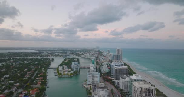 Framåt flyger över staden i skymningen. Moderna flervåningslägenhet byggnader på remsa av mark mellan havskusten och floden. Miami, USA — Stockvideo