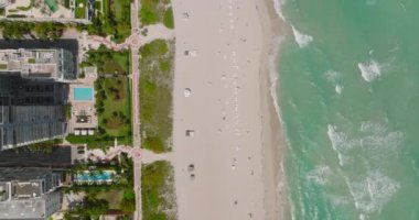 Deniz kıyısındaki kumsalın üzerinde uç. Yüzme havuzları ve palmiye ağaçları olan modern lüks oteller. Miami, ABD