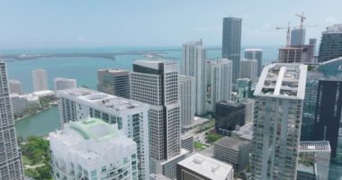 Güneşli bir günde şehir merkezindeki gökdelenlerin hava manzarası. Modern yüksek katlı ofis ya da apartman binaları ve arka plandaki su görüntülerini kaydır. Miami, ABD