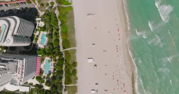 Pássaros olho tiro praia de areia alinhada por hotéis e resorts de luxo. Ondas de mar onduladas costa de lavagem. Miami, EUA — Vídeo de Stock