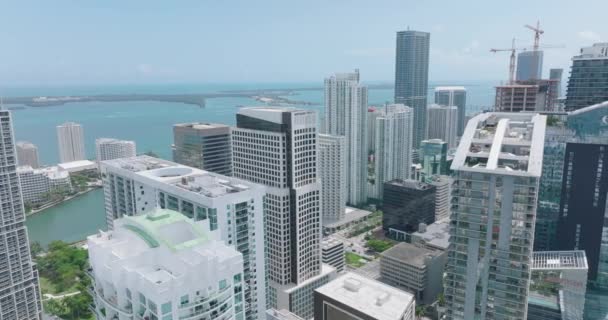 Vista aérea dos arranha-céus da baixa no dia ensolarado. Slide e pan tiro de escritórios modernos de alta elevação ou edifícios de apartamentos e água no fundo. Miami, EUA — Vídeo de Stock