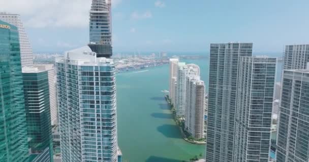 Forwards fly between tops of modern downtown skyscrapers. Revealing view of sea bay with cruising boats. Miami, USA — Vídeo de stock