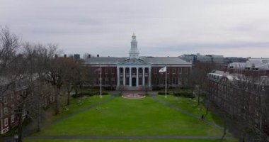 Harvard Üniversitesi şantiyesindeki Baker Kütüphanesi binasının önündeki yeşil çimlerin üzerinde geriye doğru uç. Boston, ABD