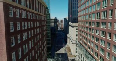 Şehir iş merkezindeki yüksek katlı ofis binaları. Kırmızı tuğlalı binalar arasında caddenin yukarısında ilerliyorlar. Boston, ABD