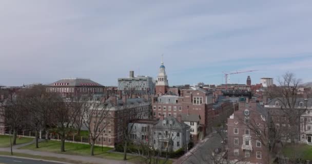 Wczesną wiosną ujęcie budynków z czerwonej cegły w kompleksie Uniwersytetu Harvarda. Przód przelatuje nad ulicą i rzędem drzew liściastych. Boston, USA — Wideo stockowe