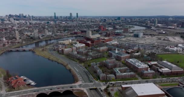 Aerial slide and shot of Harvard Business School buildings complex. Multilane road leading between site and Charles river. Cityscape with tall buildings in background. Boston, USA — 비디오