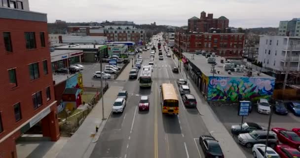 典型的なアメリカの黄色のスクールバスの前方の追跡は、都市部の忙しい通りの交通信号で停止します。ボストン,アメリカ — ストック動画