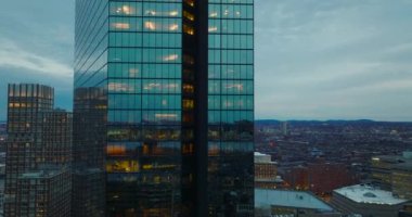 Şehir merkezindeki modern yüksek katlı ofis binasının parlak cam cephesinde dar bir uçuş. Yeni ofis kulesinin aydınlatılmış şantiyesi ortaya çıkıyor. Boston, ABD