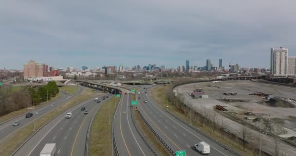 Provoz na rušné dálnici na předměstí. Zvýšený pohled na vozidla projíždějící výměnou. Vysoký kopec v centru budovy v pozadí. Boston, USA — Stock video