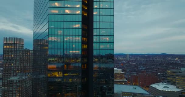 Enger Flug um die glänzende Glasfassade eines modernen Bürohochhauses in der Innenstadt. Enthüllung der beleuchteten Baustelle des neuen Büroturms. Boston, USA — Stockvideo
