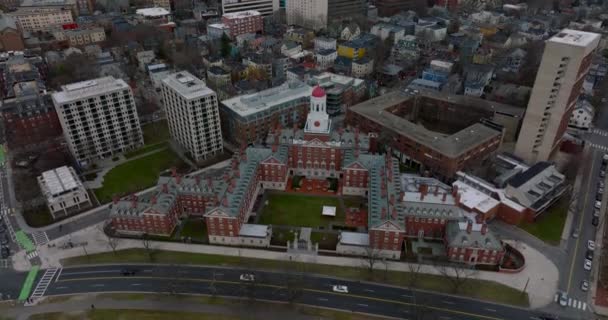 Aerial descending footage of Dunster House with grassy yard and red topped central tower. Revealing busy road on river bank. Boston, USA — Vídeo de stock