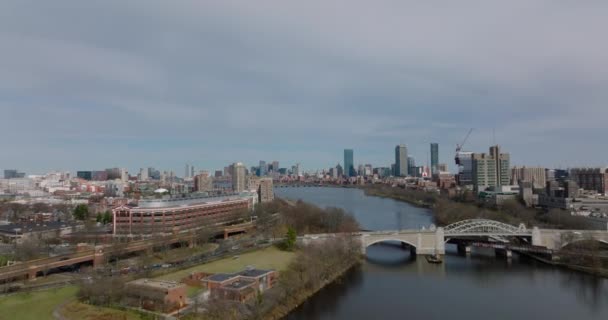 Forwards fly above Boston University Bridge over Charles river. Aerial view of cityscape with high rise business buildings. Boston, USA — Vídeo de stock