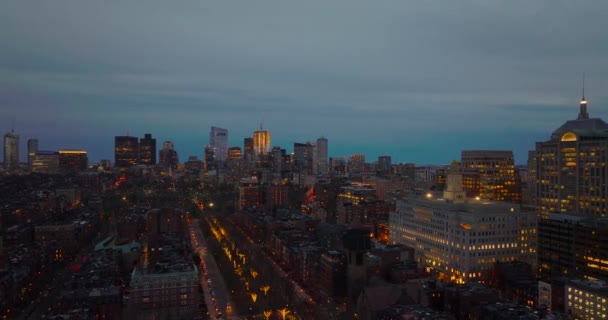 Fly above evening city. Illuminated streets and lighted windows in buildings. Aerial view of urban neighbourhood. Boston, USA — стоковое видео