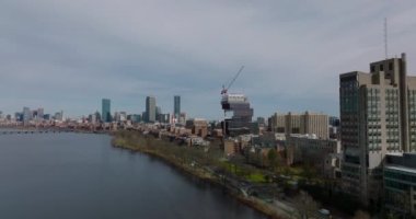 İleriye doğru, liman boyunca uçun. Modern üniversite binasının inşaatı. Arka planda şehir merkezindeki gökdelenler. Boston, ABD